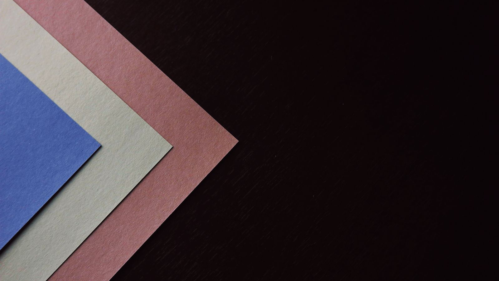 Layered sheets of colored paper stacked on a dark surface, representing a layered AI tech stack