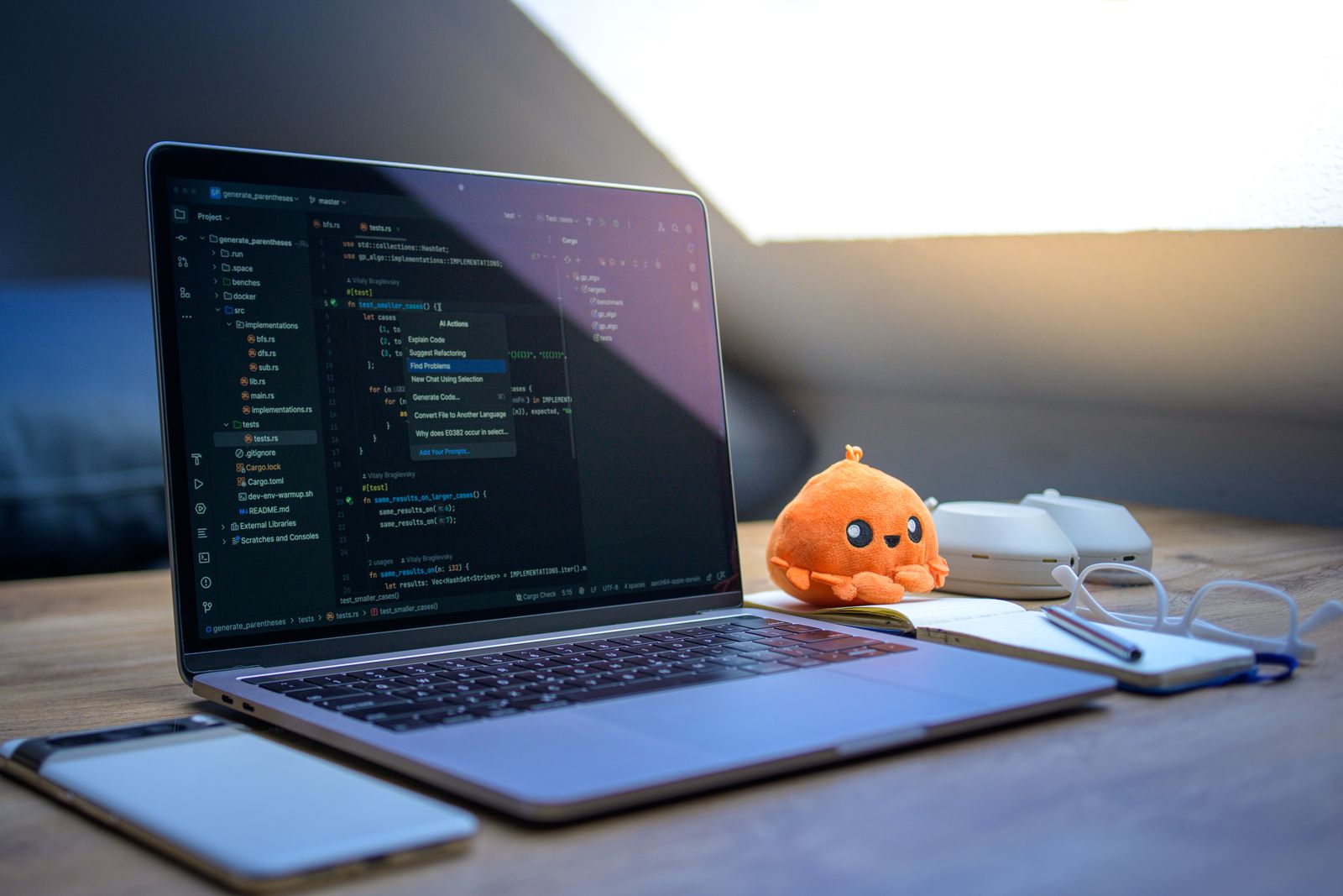 Laptop on a wooden desk showing a code editor with a project open in a modern workspace