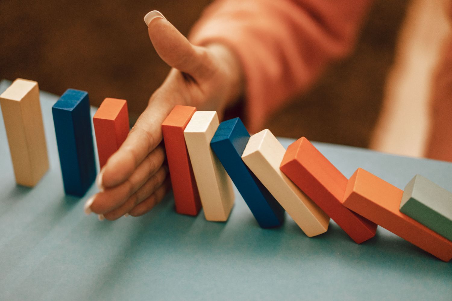 A hand stopping a chain of falling colored dominoes mid-fall, a metaphor for a Claude Code hook intercepting an action before it runs
