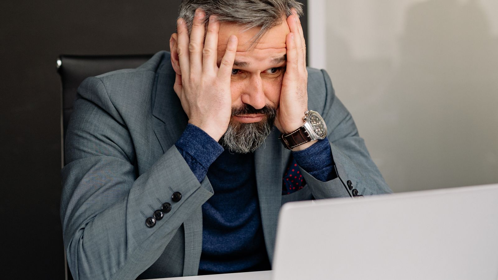 A frustrated person resting their head in their hands in front of a laptop, representing common beginner mistakes