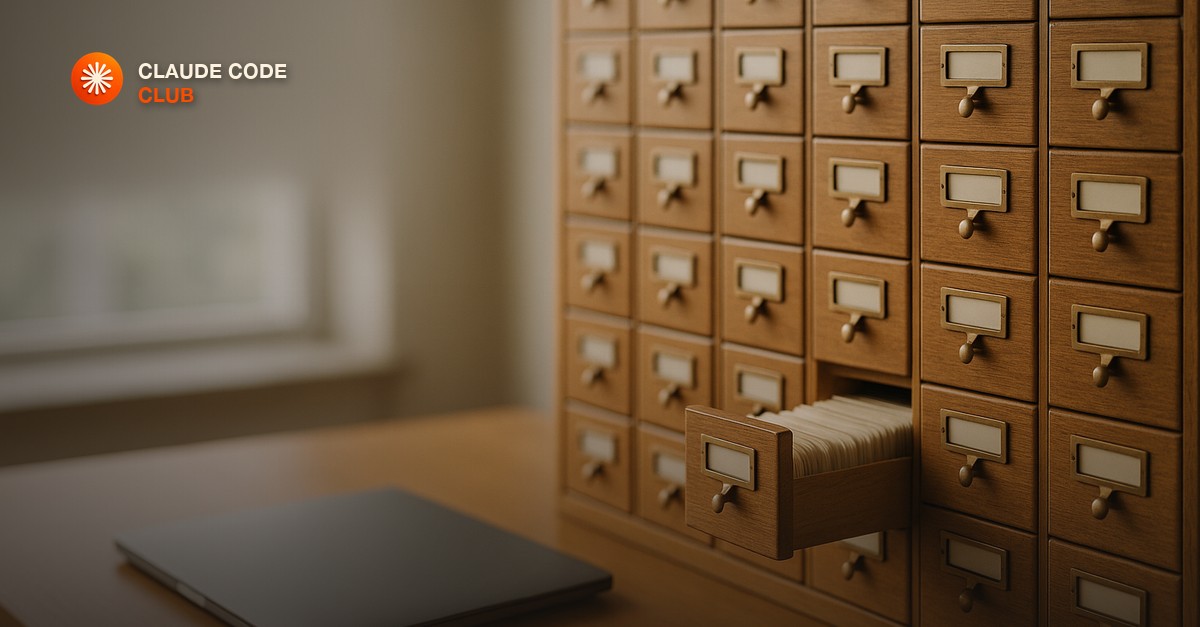 A wooden library card catalog with many labelled drawers, one drawer pulled open beside a closed laptop