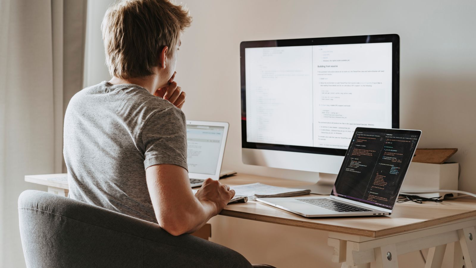 A developer at a desk reading setup docs across multiple screens