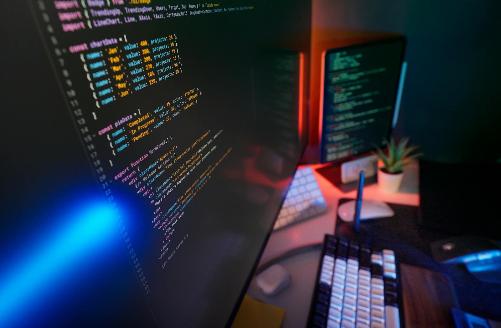 Colorful keyboard backlit on a programmer's desk with code editor open in the background