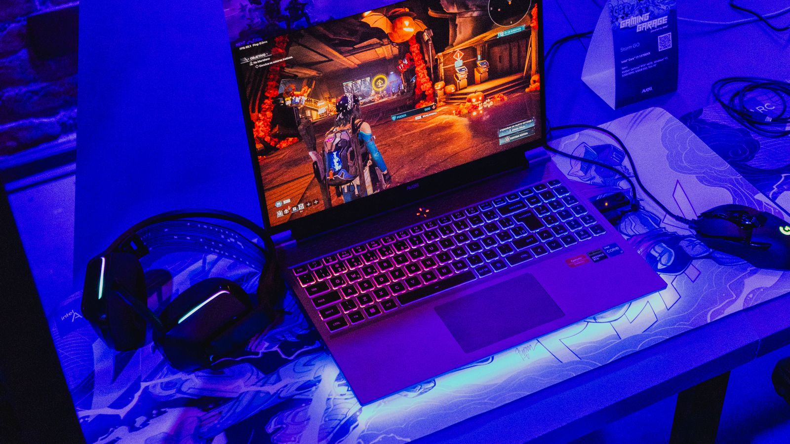 Gaming laptop with a headset on a desk lit by purple and blue neon light