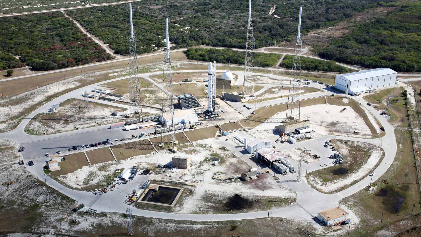 An aerial view of a rocket standing on a launch complex, ready for liftoff