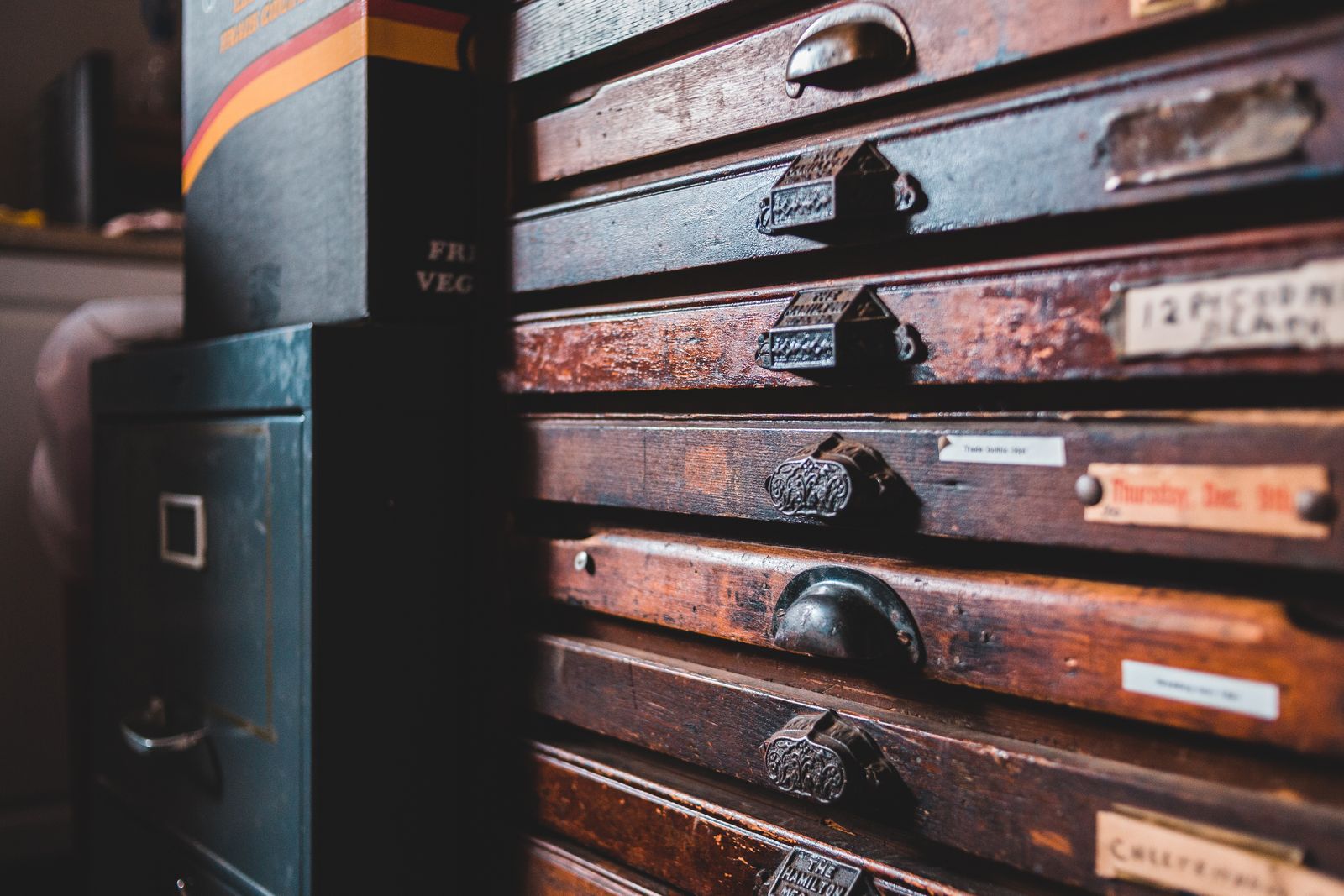 Rows of antique wooden filing cabinet drawers with brass card labels - a memory archive metaphor