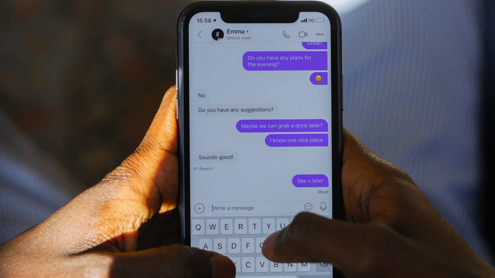 Hands holding a phone showing a messaging app chat.