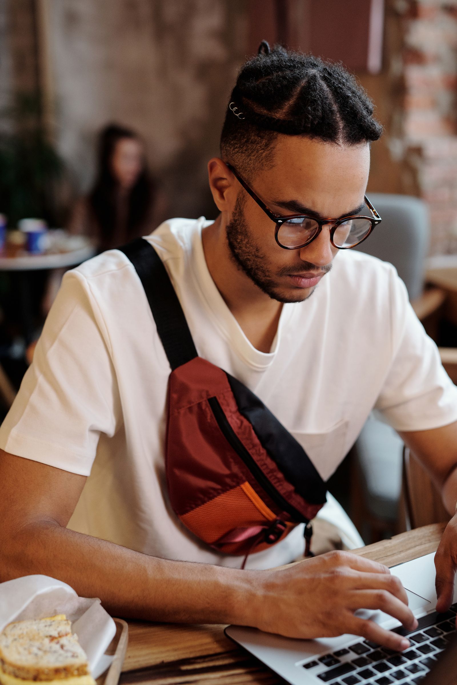 Focused freelancer in glasses working on a laptop at a cafe table
