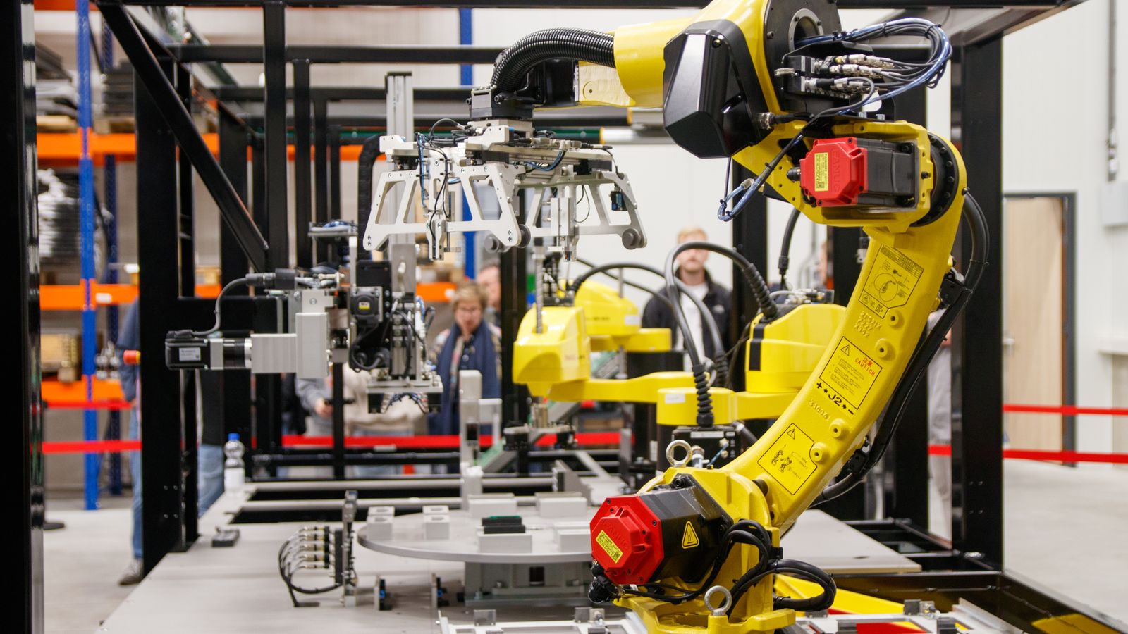 A yellow industrial robot arm working in an automated manufacturing cell