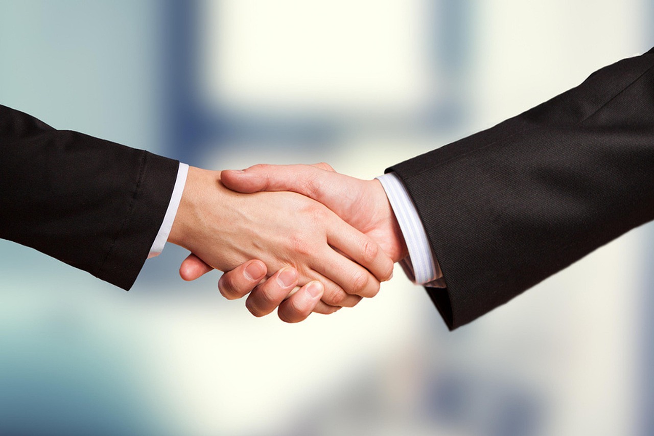 Two people shaking hands across a desk to seal a business agreement