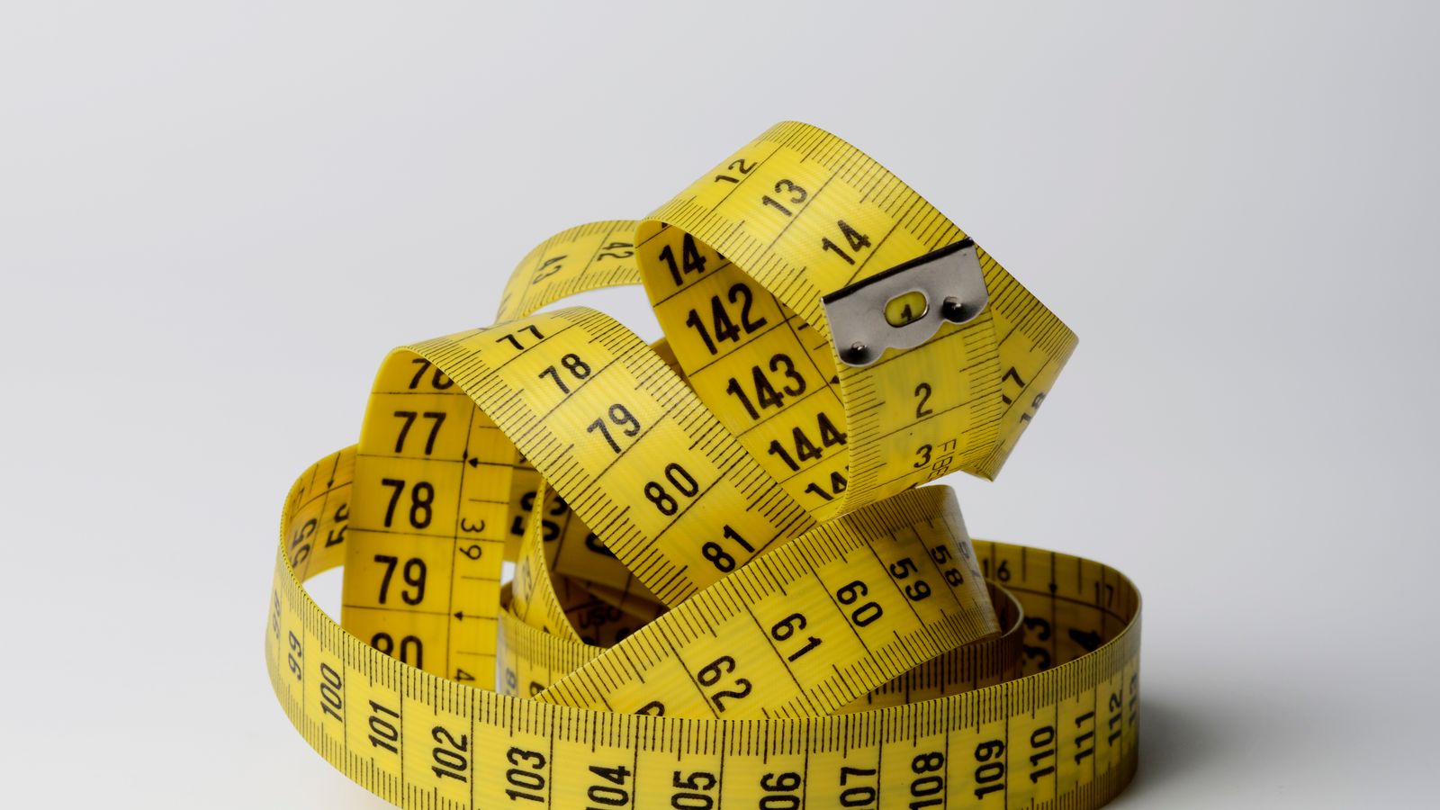 A yellow measuring tape coiled into a tangle.
