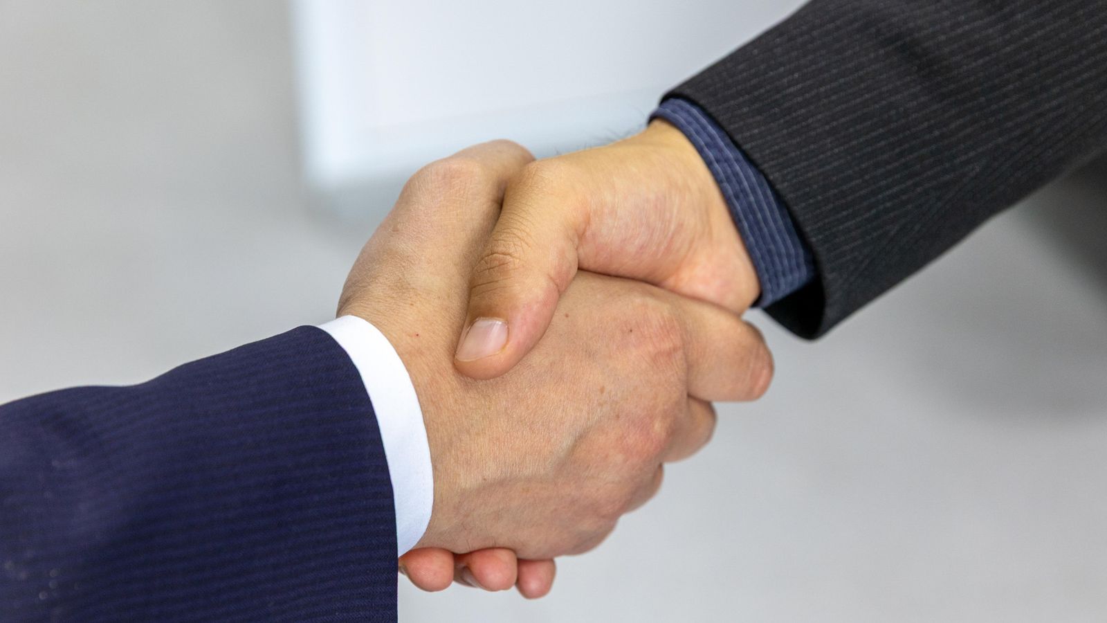 Two people in suits shaking hands.