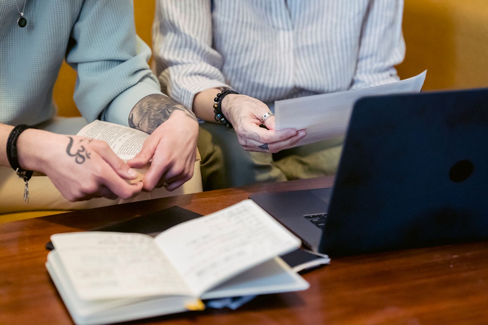 Two coworkers reviewing project notes and a laptop together at a table