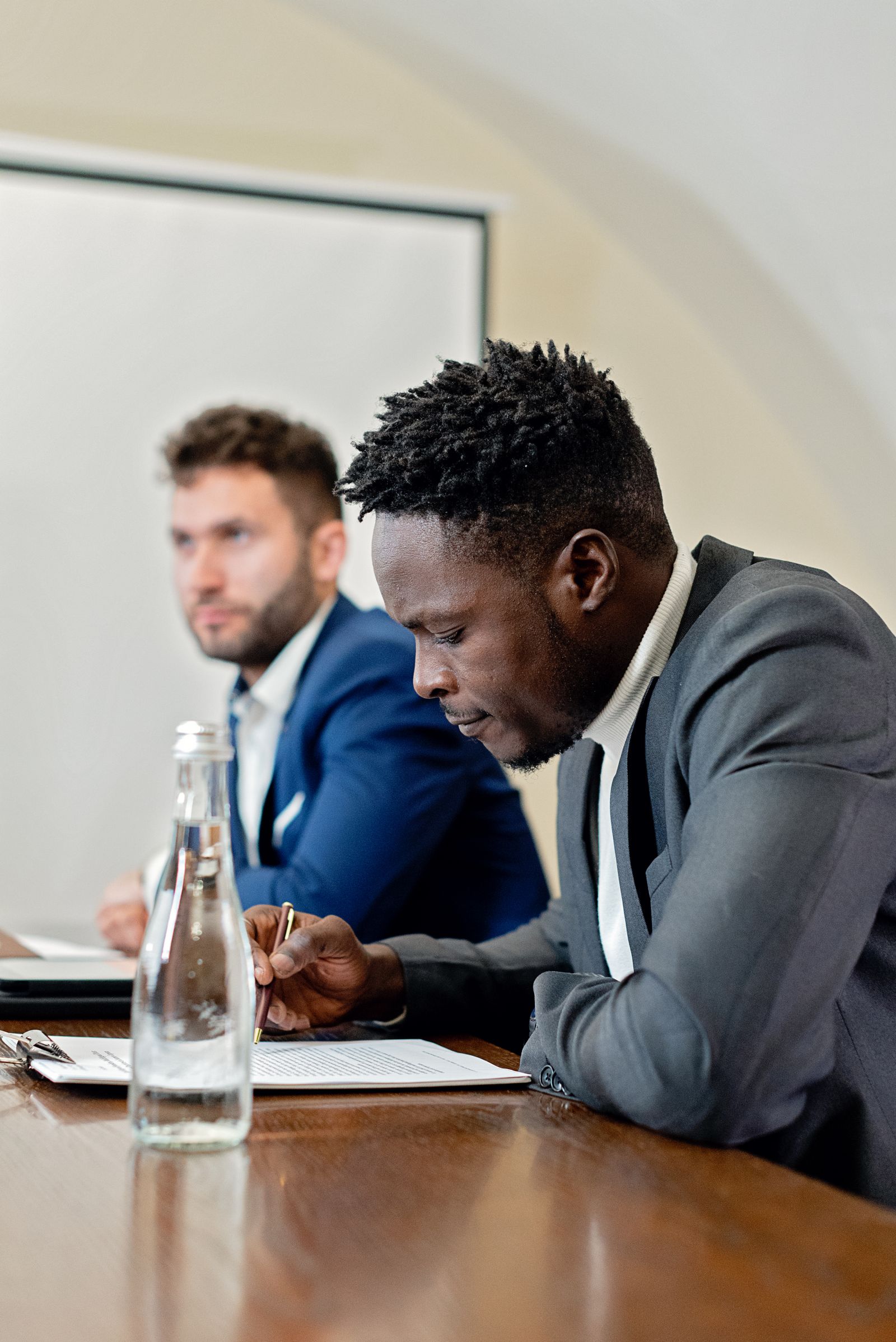 Two professionals reviewing a printed contract across a table in a meeting room