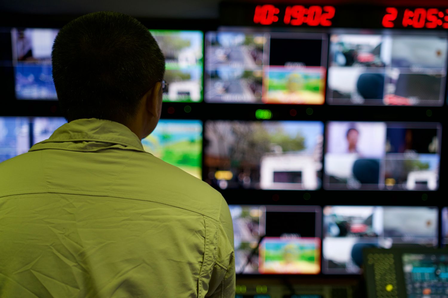 A person watching a wall of monitors in a control room, representing running several client projects from one command center in Claude Code