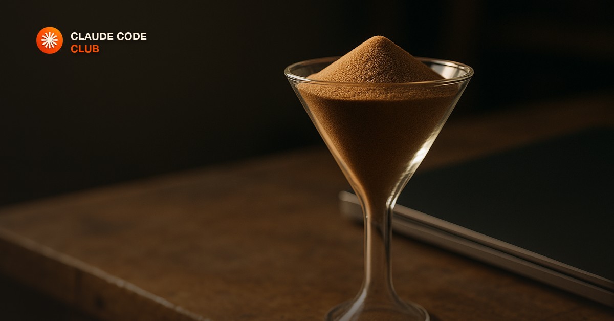 A narrow glass funnel with fine sand backed up above the neck on a workbench, beside a closed laptop